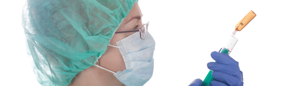 Eine Ärztin mit Baretthaube zieht eine medizinische Spritze auf