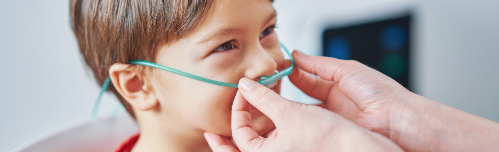 Eine Ärztin legt einem Jungen eine Brille des Sauerstoffsystems an