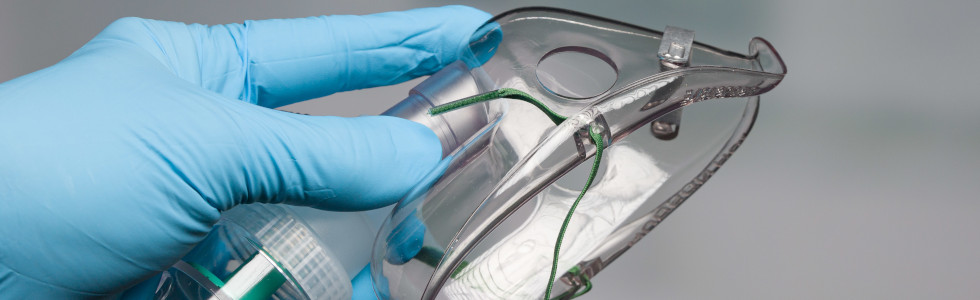 Ein Arzt Teile des Sauerstoffsystems – eine Sauerstoffmaske – in die Kamera.