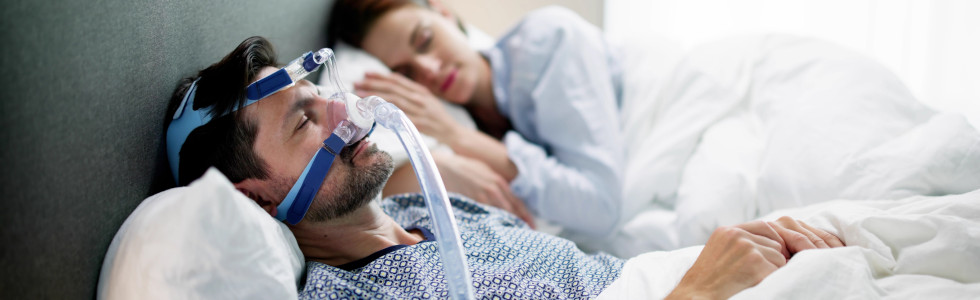 Ein Mann trägt eine medizinische Nasenmaske beim Schlafen im Bett