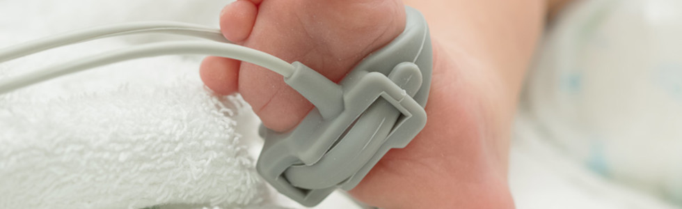 Pulsoximeter-Sensor am Fuß eines Säuglings im Bett