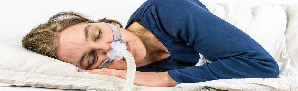 Eine Frau trägt eine CPAP-Maske mit einem CPAP-Schlauch