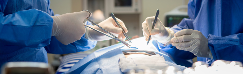 Ein Chirurg und eine Assistentin nähen die Wunde einer Person im OP-Saal zu – jetzt chirurgisches Nahtset kaufen!