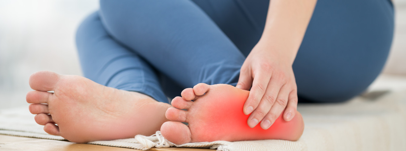 Eine Frau hat Schmerzen – sie hält sich den diabetischen Fuß