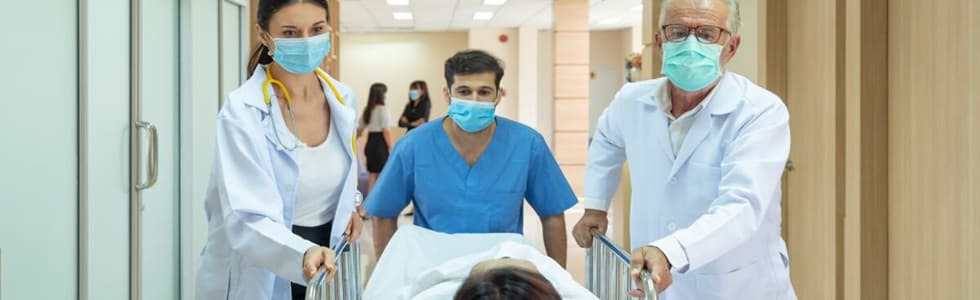 Ein Mann wird von Ärzten in den Operationssaal geschoben – er ist mit einer Patientendecke bedeckt