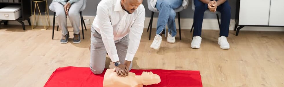 Eine Gruppe an Personen nimmt an einem erste Hilfe Training mit einer CPR Puppe teil