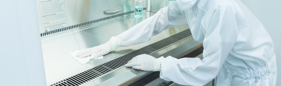 Ein Laborant nutzt Desinfektionstücher aus dem Sortiment für die Reinigung einer Laborfläche