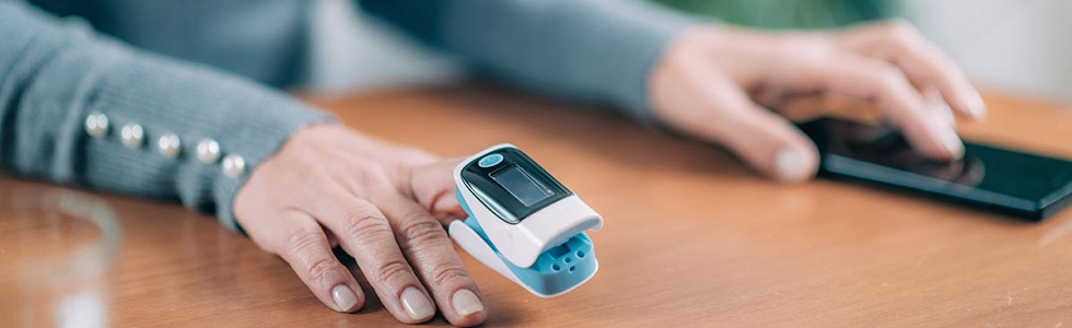 Nahaufnahme vom Anlegen eines Pulsoximeter-Sensors am Finger einer Patientin