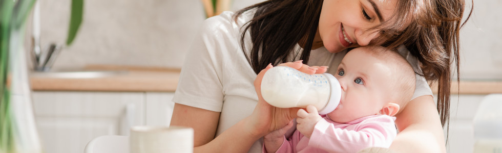 Eine Frau füttert ihr Baby – sie war einen Flaschenwärmer kaufen