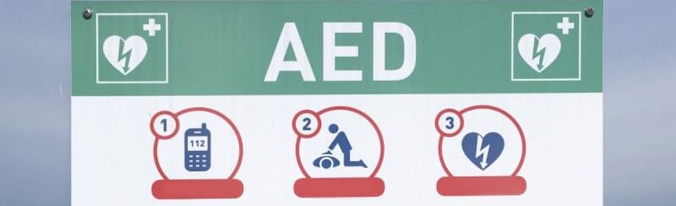 Ein AED hängt einsatzbereit an einer Wand