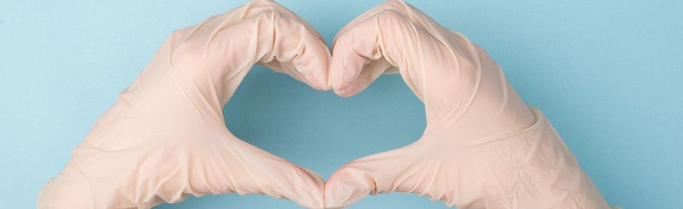 Eine Person mit weißen Handschuhen an den Händen formt ein Herz – jetzt Handschuhspender kaufen!