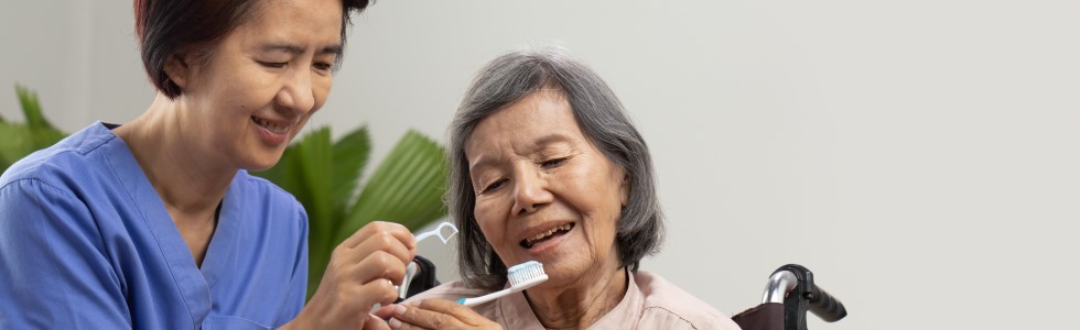 Eine Krankenschwester hilft einer Seniorin bei der Nutzung von medizinischen Mundpflegeprodukten