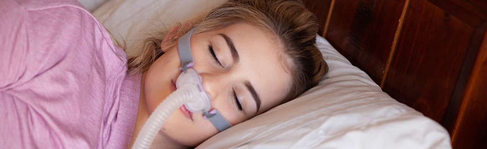 Frau schläft ruhig dank perfekt sitzender CPAP-Maske