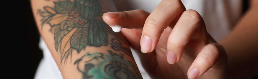 Auf einen tätowierten Unterarm wird Tattoo-Creme aufgetragen