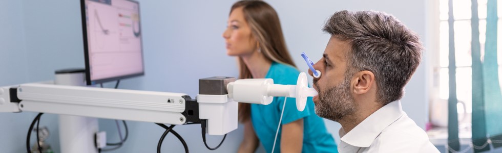 Ein Mann prüft die Funktion seiner Lunge mit einem Spirometer