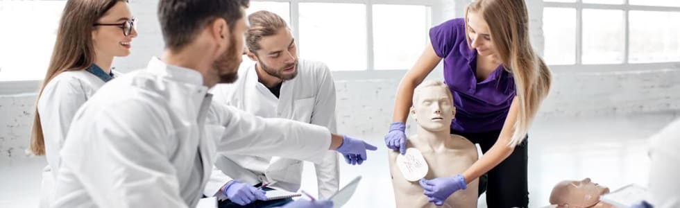 Ein Mann weist Mitarbeiter in die Nutzung von einem AED ein