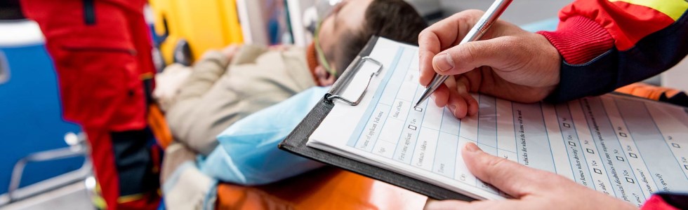 Notfallsanitäter trägt Daten eines Notfallpatienten auf Klemmbrett ein – Organisationsmittel erlauben effektives Arbeiten
