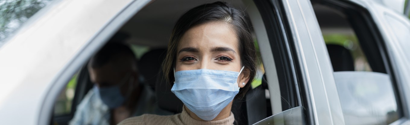 Eine Frau trägt eine Maske als Inhalt des Verbandkastens für das Auto