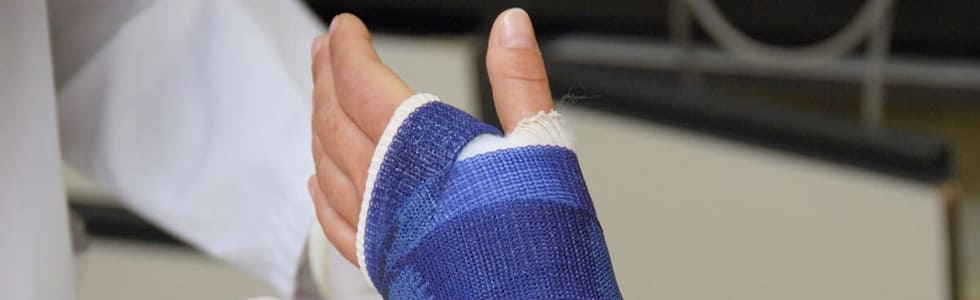 Arzt versorgt gebrochenen Arm mit Gipsverband aus dem Verbandsmaterial Sortiment