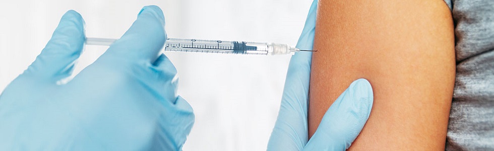 Arzt spritzt Patienten eine Impfung mit einer Spritze und einer Einmalkanüle