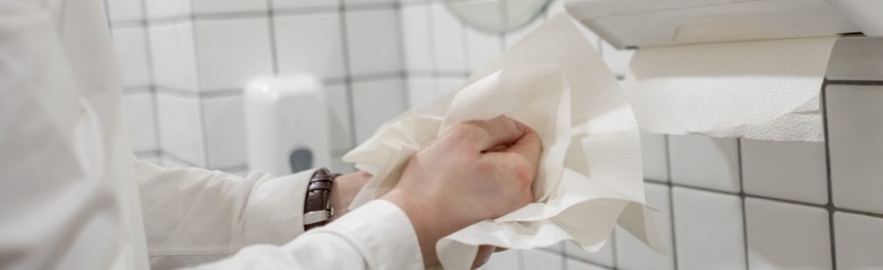 Ein Arzt nutzt Papierhandtücher, um sich die Hände hygienisch abzutrocknen