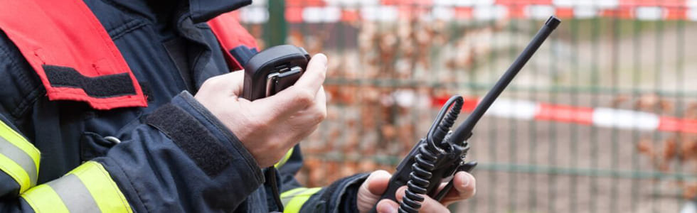 Ein Feuerwehrmann hat ein Funkgerät in der Hand – nach der Nutzung kann er es in einen Rettungsdienst Holster stecken