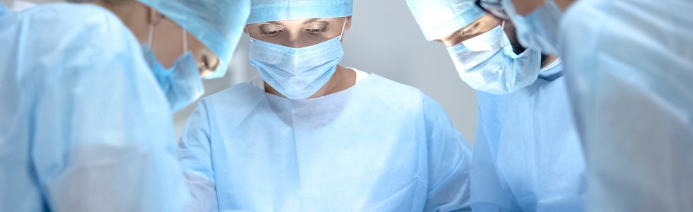 Mehrere Ärzte in OP-Bekleidung operieren einen Patienten