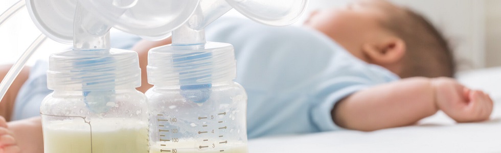 Ein Baby liegt neben zwei Milchpumpen – die Mutter hat Babybedarf gekauft.